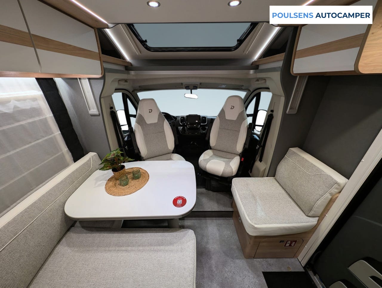 Salon en L du camping-car semi-intégré Dethleffs Just Camp T 7052 2026 avec banquettes confortables et table autoportante